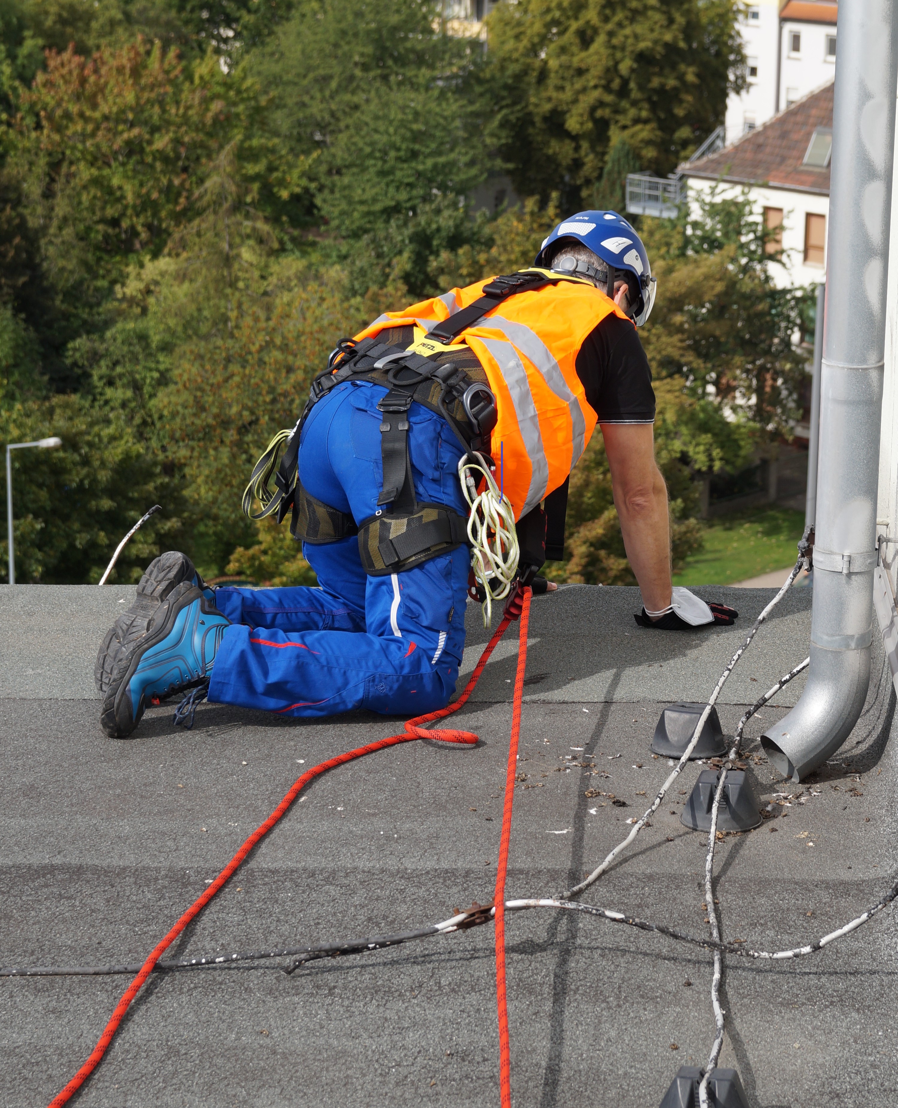 Eine Person kniet an einer Dachkante und schaut hinunter.